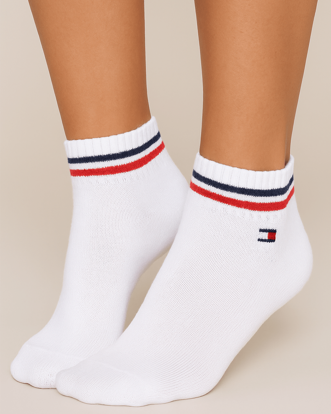 White Tommy ankle socks with red and navy stripes and logo patch, worn on feet, showing soft sporty design and comfortable everyday fit.